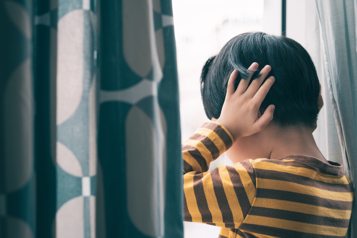 Little Asian boy wear long sleeve stripe shirt stand by window, hand cover ears, crying and screaming. Feeling frustration, anxiety, fear, stressed. Domestic violence, Autism, Bipolar disorder and mental illness concept.